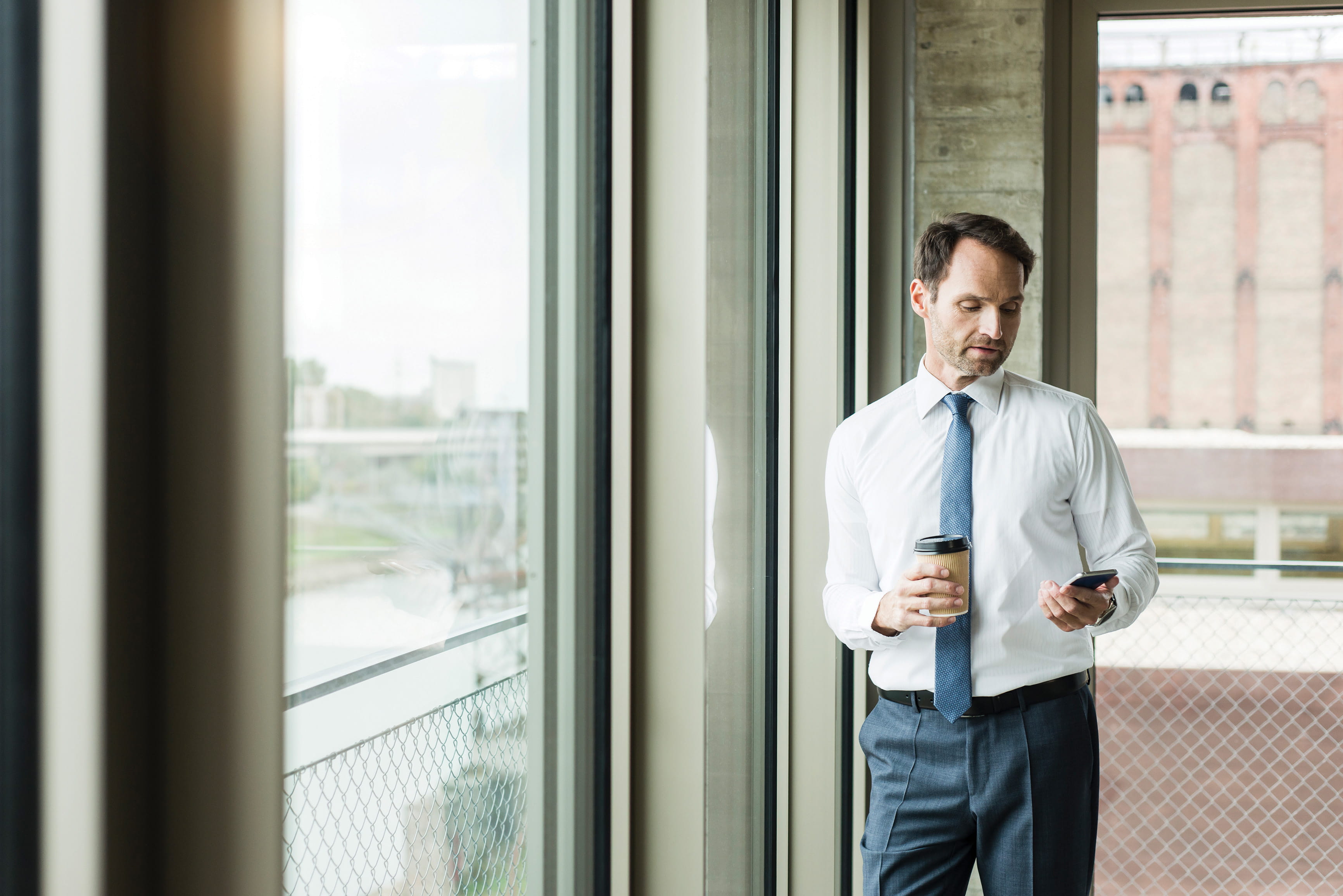 man in tie looks at his cell phone